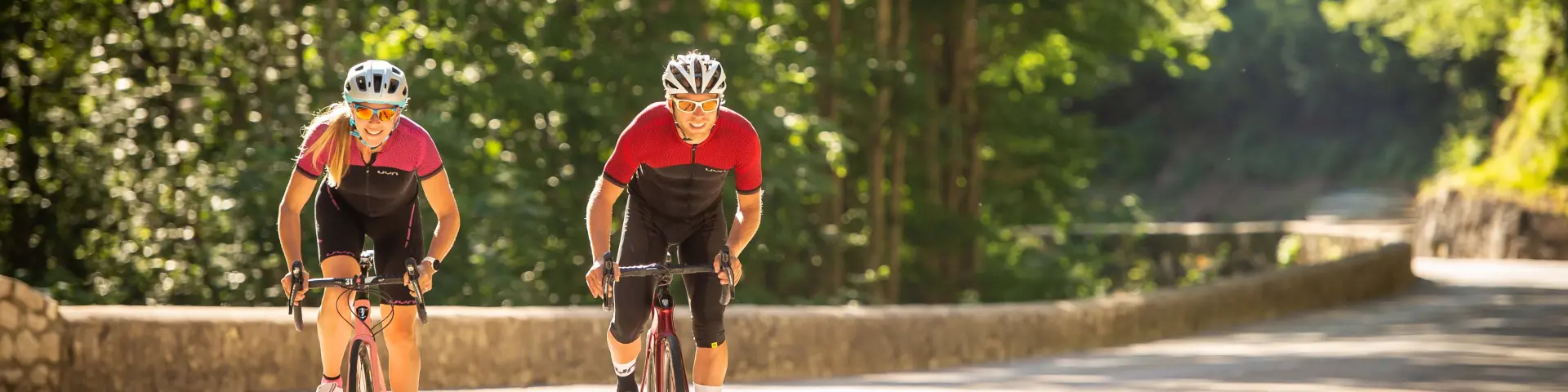 Deux cyclistes en tenue rouge et casque jaune roulant sur une piste forestière