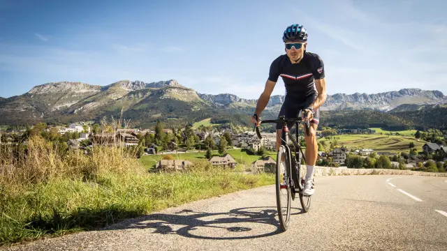Cycliste en tenue de sport sur une route de montagne bordée de végétation