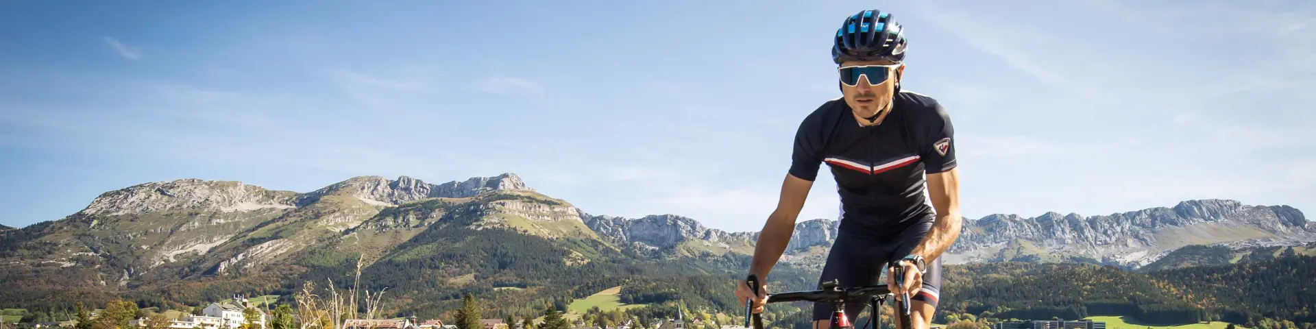 Cycliste en tenue de sport sur une route de montagne bordée de végétation