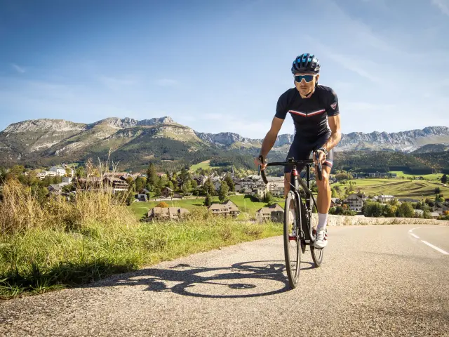 Cycliste en tenue de sport sur une route de montagne bordée de végétation