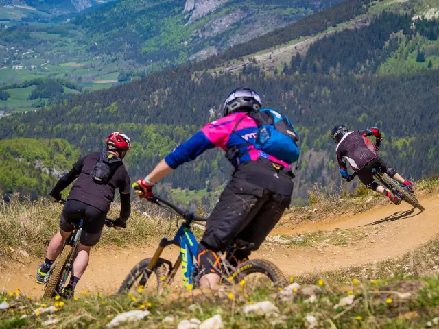 Tre escursionisti con bastoncini da trekking su un sentiero di montagna, con valli e vette sullo sfondo
