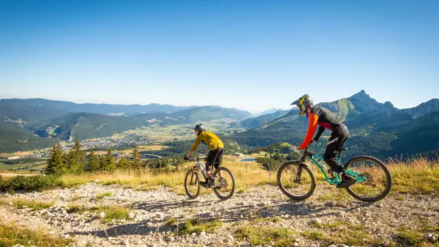 Deux cyclistes en tenue de compétition gravissent une pente rocheuse en montagne