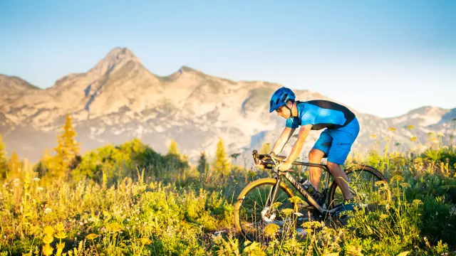 Cycliste portant un casque bleu et une veste fluorescente sur un vélo de montagne en terrain accidenté