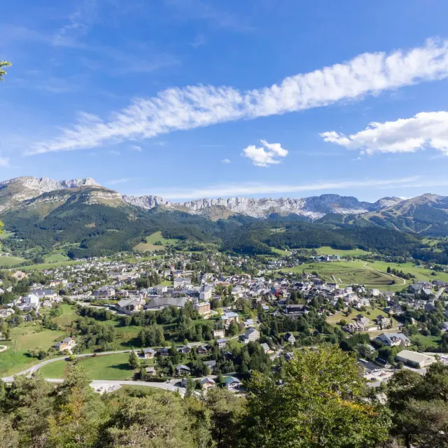 Village surrounded by green hills under a blue sky with white clouds