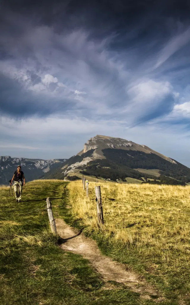 Due escursionisti su un sentiero di montagna con nuvole basse e una cresta rocciosa sullo sfondo