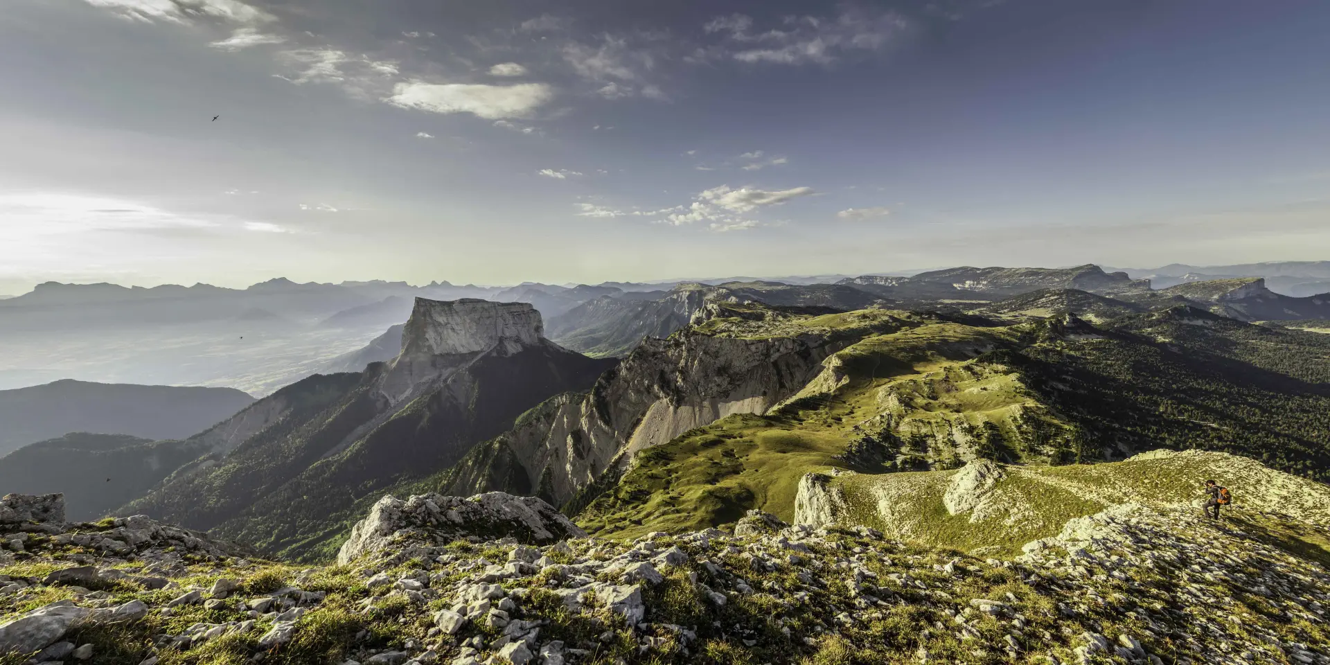 View of a mountain range with rocky peaks and dense vegetation under a stormy sky
