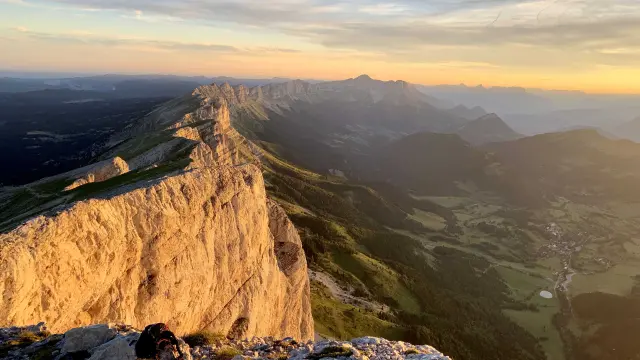 Falaises escarpées éclairées par le soleil couchant, avec des rochers épars en contrebas
