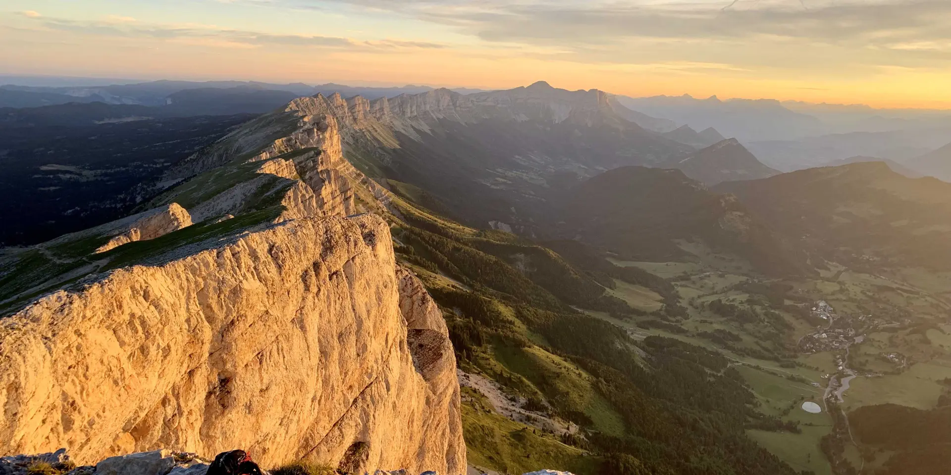 Falesie scoscese illuminate dal sole al tramonto, con rocce sparse in basso