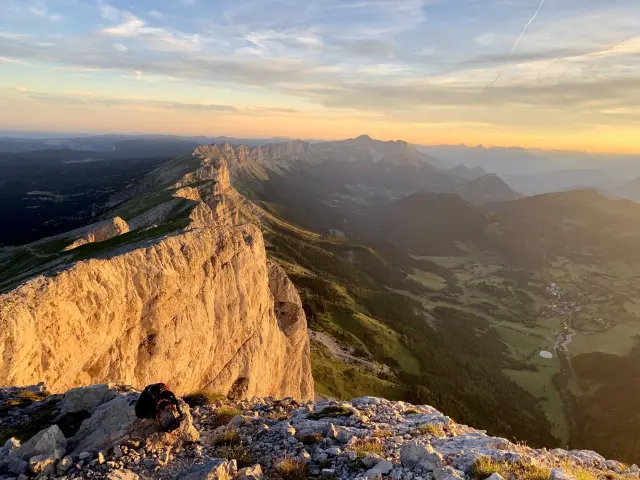 Falesie scoscese illuminate dal sole al tramonto, con rocce sparse in basso