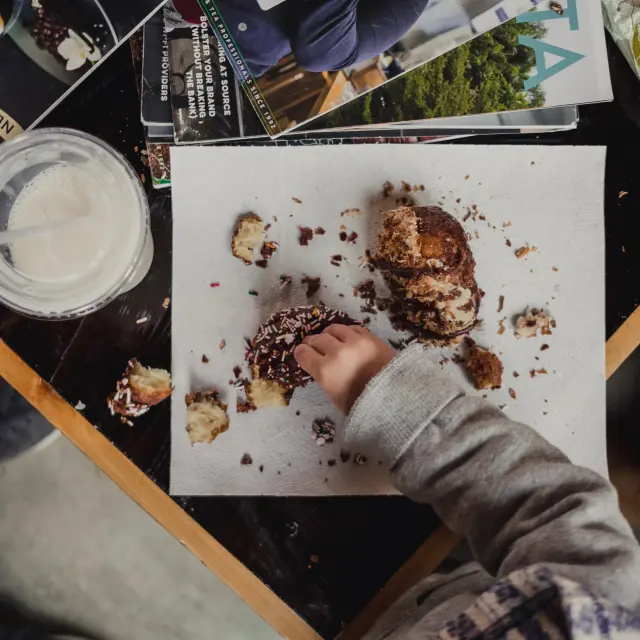 Main tenant un cookie recouvert de pépites de chocolat et de noix, posé sur une plaque de cuisson