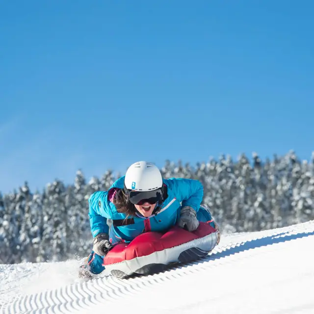 Skieuse en combinaison bleue et rouge glissant sur une pente enneigée