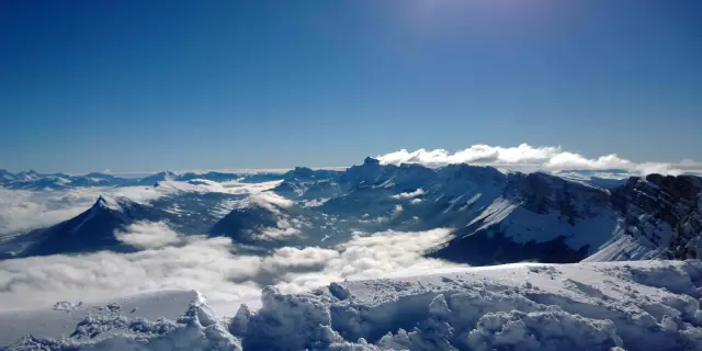 Montagne innevate con valli e creste rocciose sotto un cielo blu chiaro