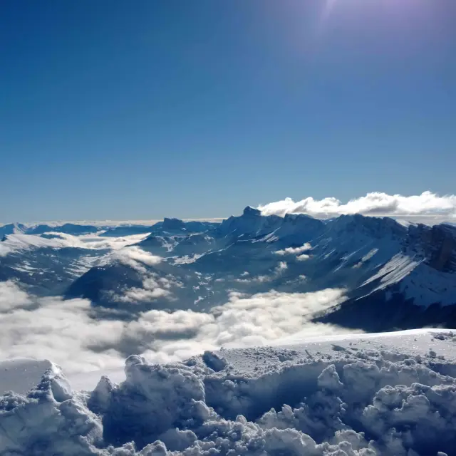 Montagne innevate con valli e creste rocciose sotto un cielo blu chiaro