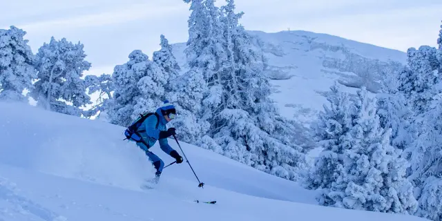 Personne en train de skier sur une pente enneigée en montagne
