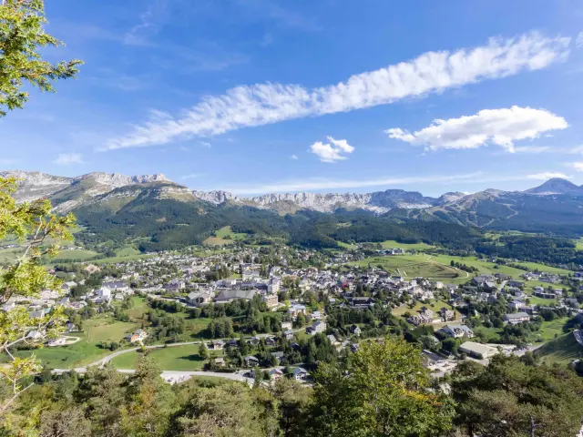 Village de montagne entouré de collines verdoyantes et de bâtiments dispersés