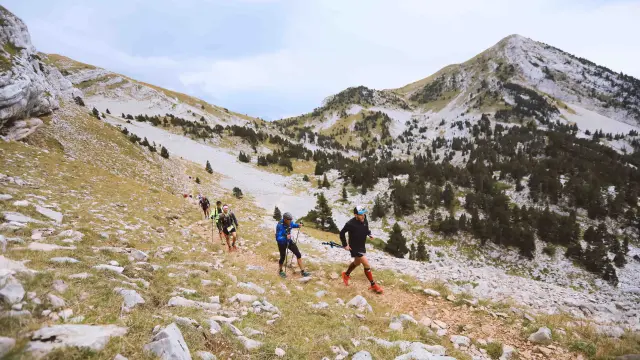 Groupe de randonneurs marchant sur un sentier en montagne avec des sommets enneigés en arrière-plan