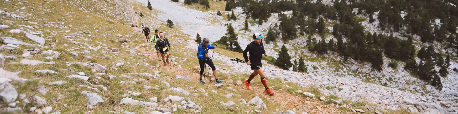 Groupe de randonneurs marchant sur un sentier en montagne avec des sommets enneigés en arrière-plan