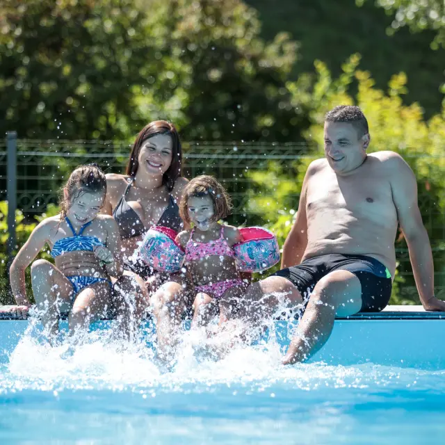 Quatre personnes sur un pédalo dans une piscine, éclaboussant l’eau avec des pistolets à eau