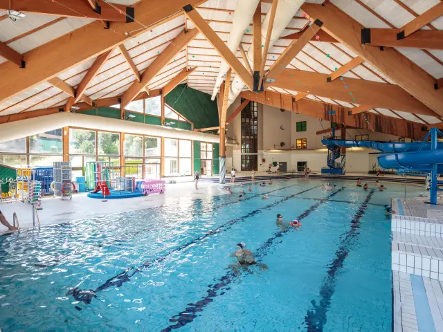Piscine intérieure avec des voûtes en bois et des nageurs en activité