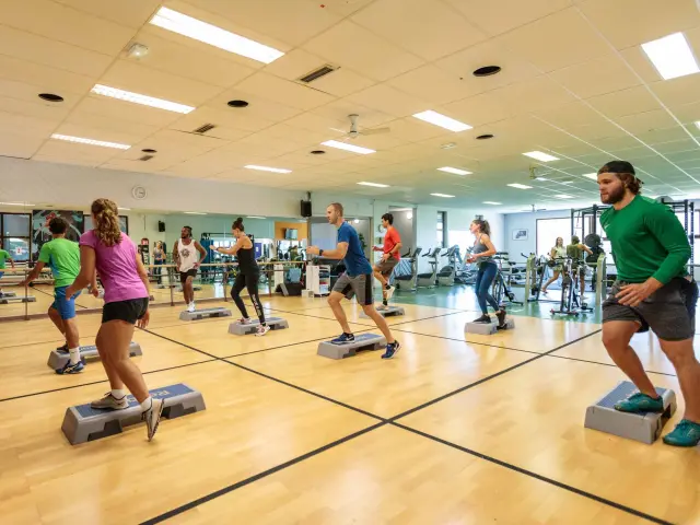 Salle de sport avec des personnes pratiquant des exercices au sol sous des lumières LED