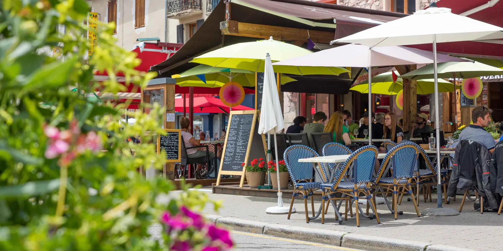 Terrasse de café en bord de port avec des tables, chaises et parasols blancs
