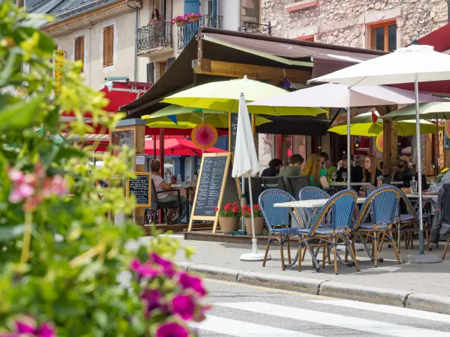 Terrasse de café en bord de port avec des tables, chaises et parasols blancs