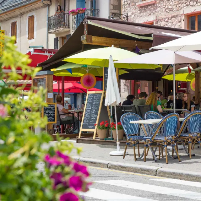 Terrasse de café en bord de port avec des tables, chaises et parasols blancs