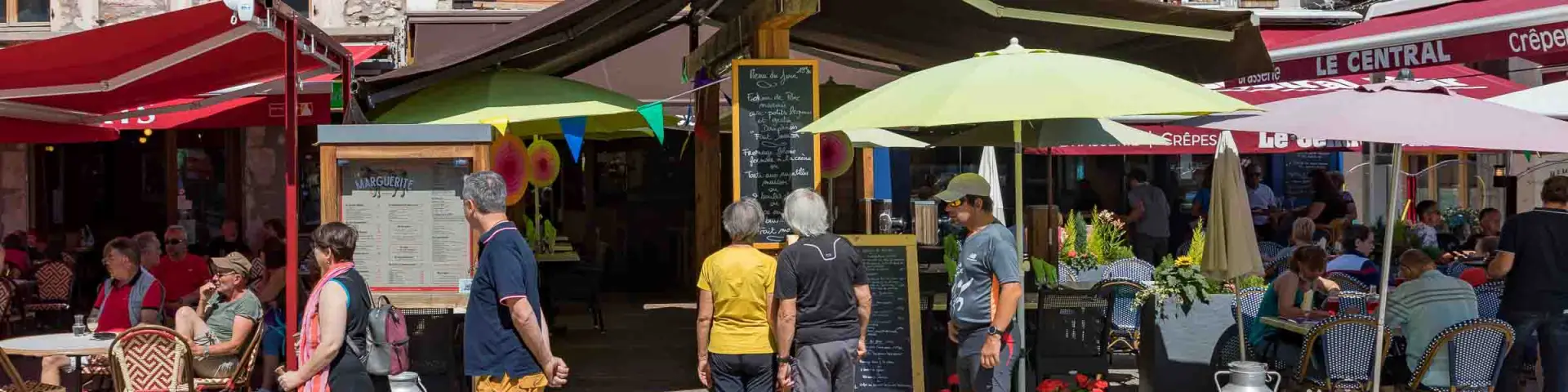 Mercato all'aperto con bancarelle e clienti di fronte a una locanda chiamata Restaurant