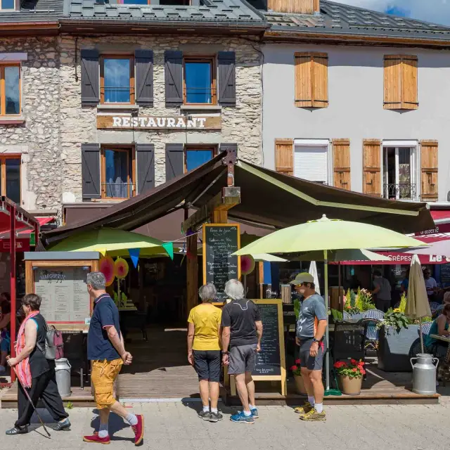 Marché en plein air avec des étals et des clients devant une auberge nommée Restaurant