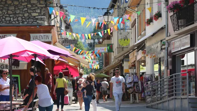 Rue commerçante avec guirlandes lumineuses et passants sous des parasols roses