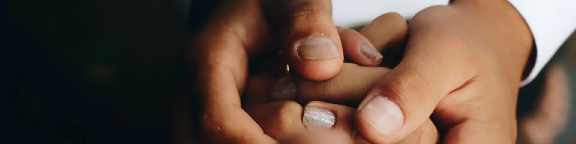 Left hand holding a gold wedding ring with a diamond