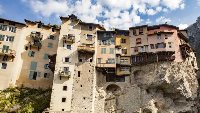 Maisons en pierre empilées sur une colline, avec une falaise rocheuse en arrière-plan