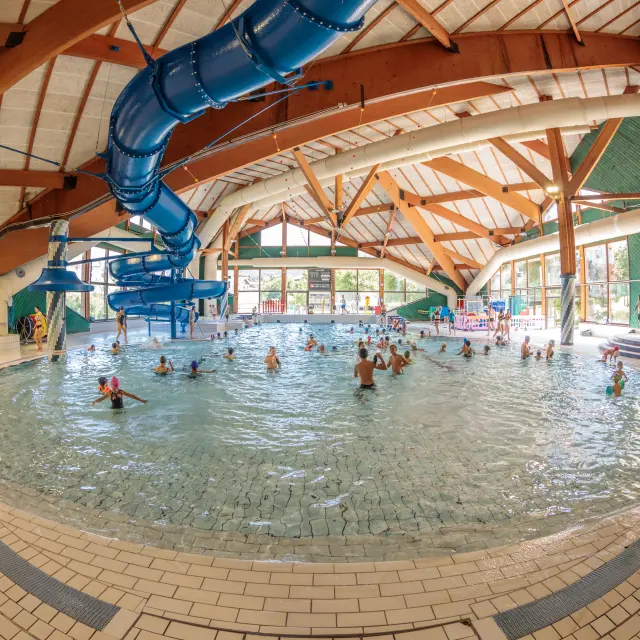 Piscine intérieure circulaire avec des voûtes en bois et des baigneurs