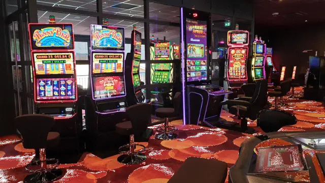 Intérieur d'une salle d'arcade avec plusieurs bornes de jeux lumineuses et des joueurs assis