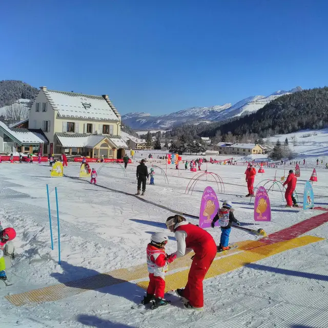 Bambini in abbigliamento da sci che seguono un istruttore su una pista segnalata