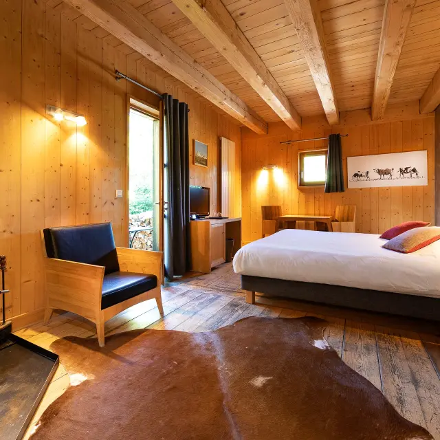 Camera d’albergo spaziosa con letto matrimoniale, divano, tavolino e vista mare attraverso una vetrata