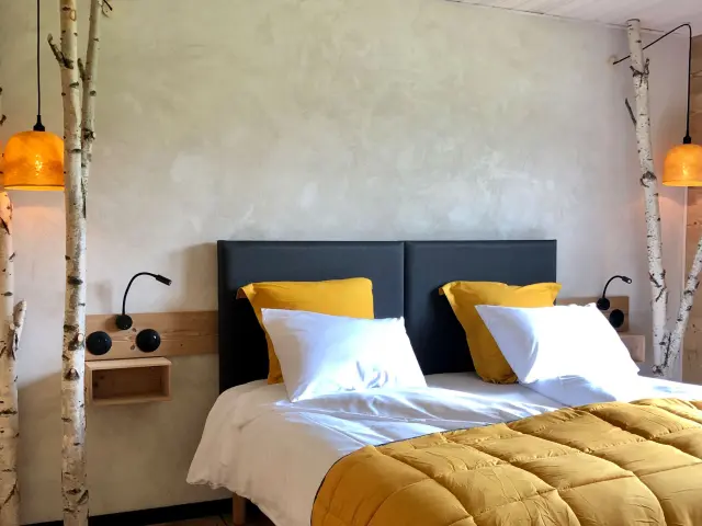 Chambre d'hôtel équipée de deux écrans plats posés sur une table de chevet et d'un lit double