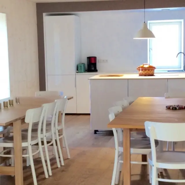 Cucina attrezzata con isola centrale, sgabelli e elettrodomestici bianchi