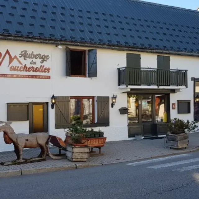 Façade d'une boutique de chocolatier avec des vitrines exposant des produits et des tables en terrasse