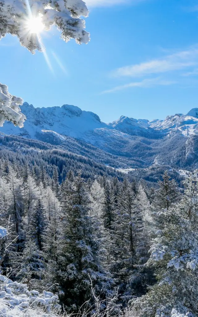 Versante roccioso innevato con montagne sullo sfondo sotto un cielo sereno