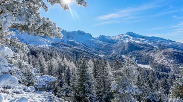 Versante roccioso innevato con montagne sullo sfondo sotto un cielo sereno