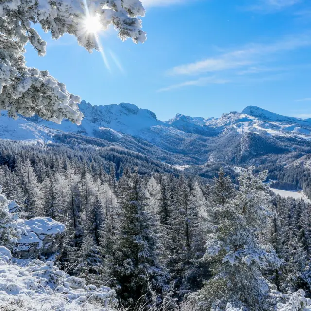 Versante roccioso innevato con montagne sullo sfondo sotto un cielo sereno