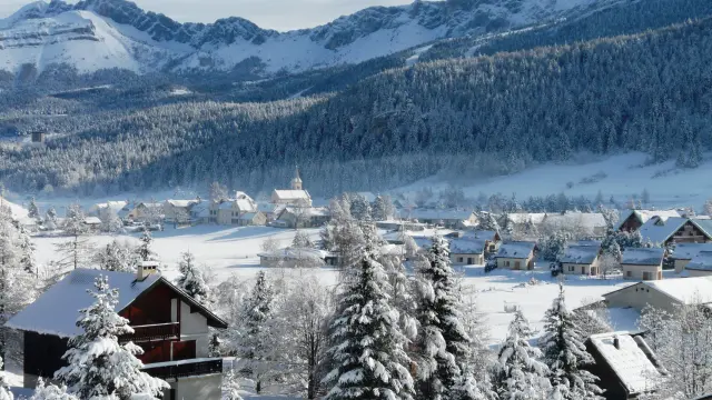 Porto di montagna coperto di neve con edifici e barche a vela ormeggiate