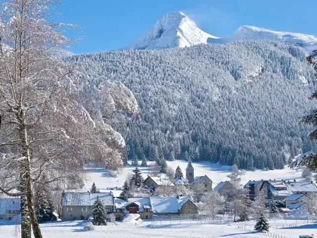 Villaggio di montagna coperto di neve con chalet e abeti innevati