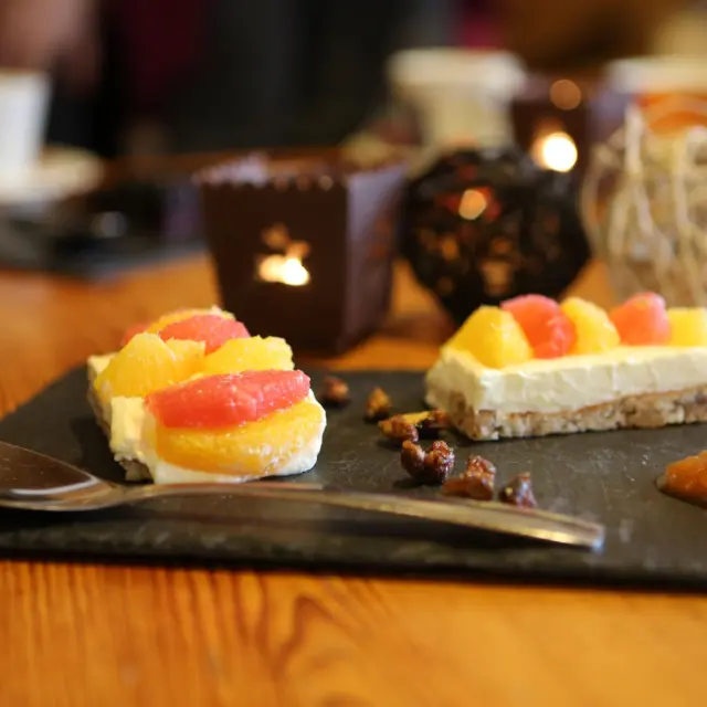 Trois desserts à base de fruits frais et de crème sur une assiette en ardoise