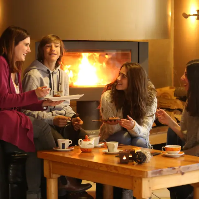 Quatre femmes assises autour d'une table en bois, discutant et buvant dans des verres