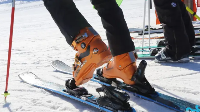 Skater con casco e giacca arancione che esegue una figura su una rampa in cemento