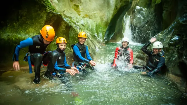 Groupe de personnes en combinaison de rafting sur un cours d’eau en pleine forêt