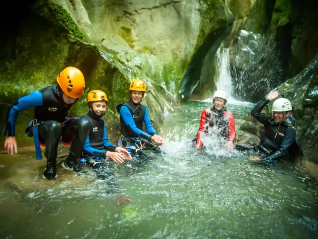 Groupe de personnes en combinaison de rafting sur un cours d’eau en pleine forêt