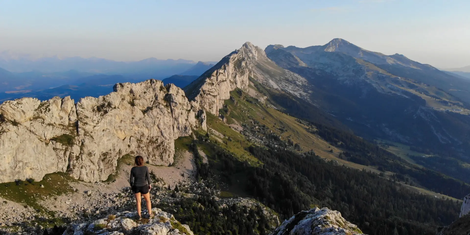 Deux personnes en randonnée sur un sentier rocheux en montagne, avec vue sur une mer et des îles en arrière-plan